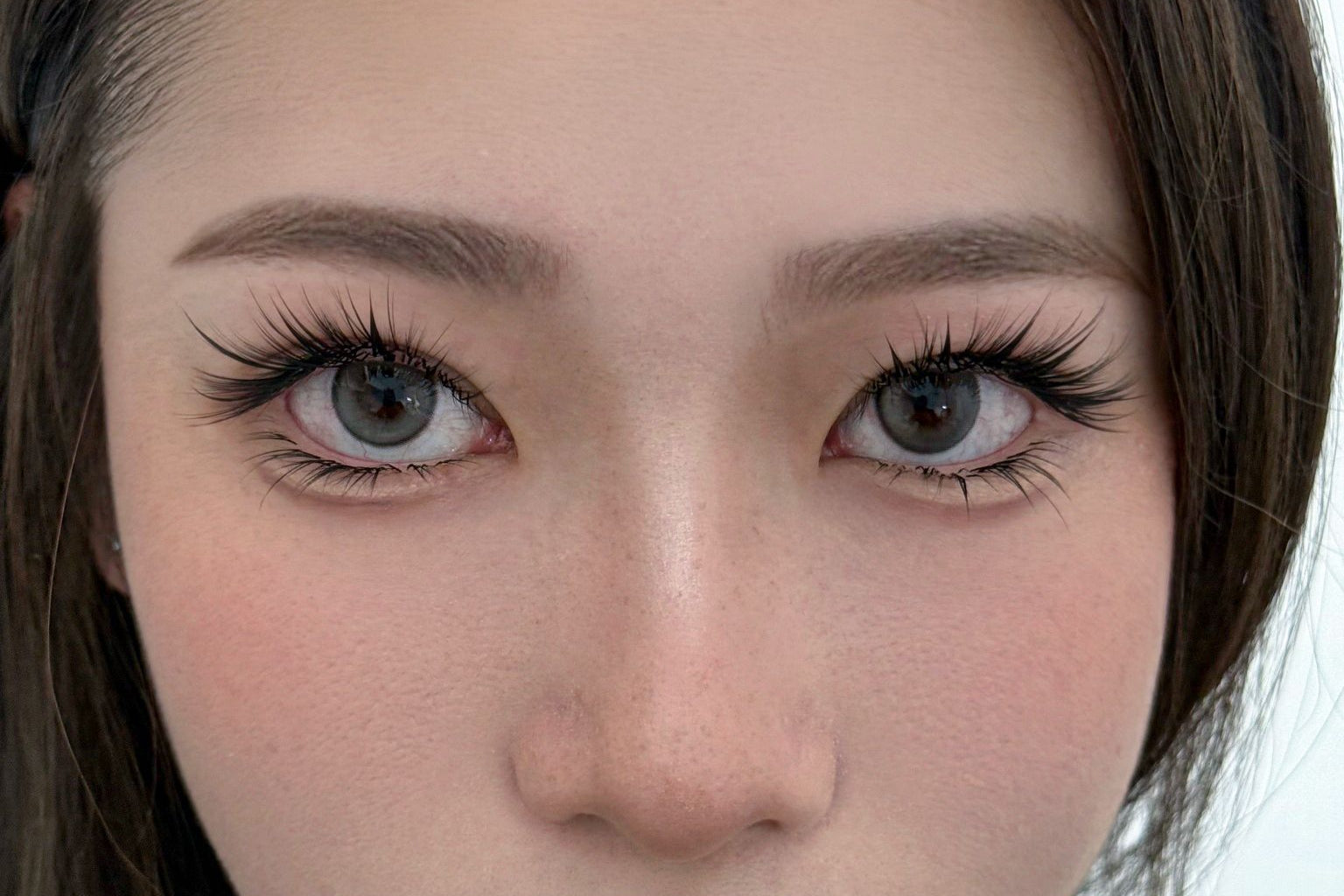 Close-up of a person with long eyelashes and neutral expression